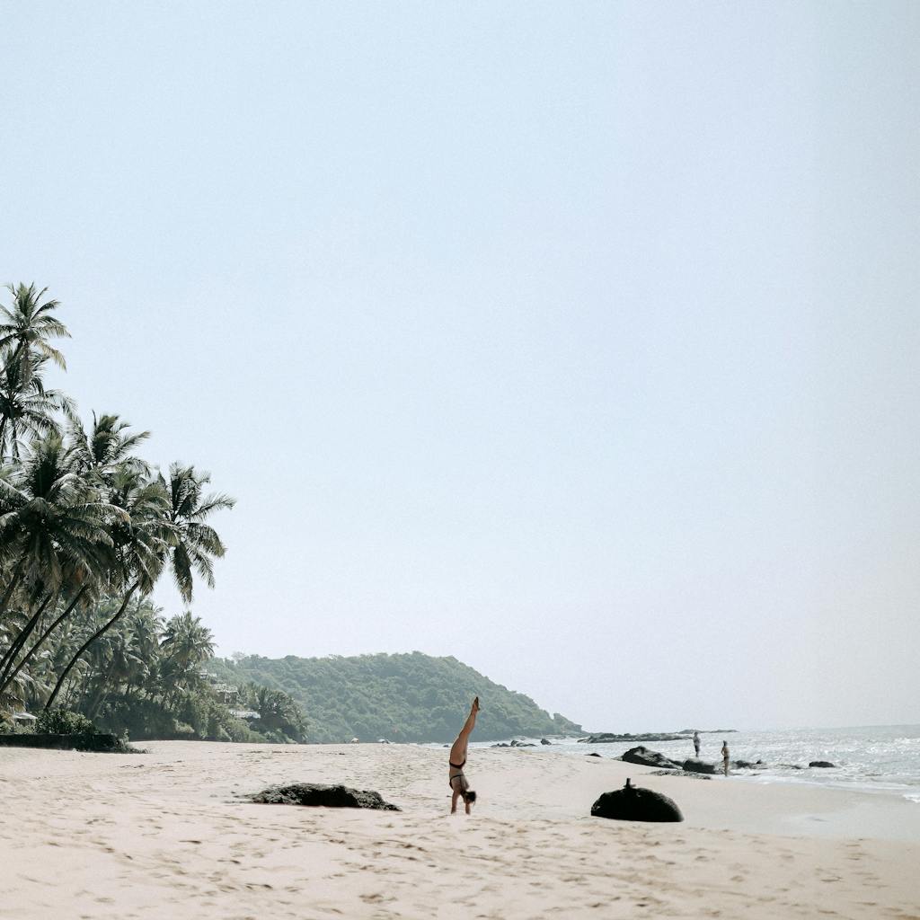 Woman Standing on Hands on Beach with Palm Trees